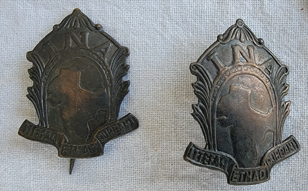 Two I.N.A. metal badges